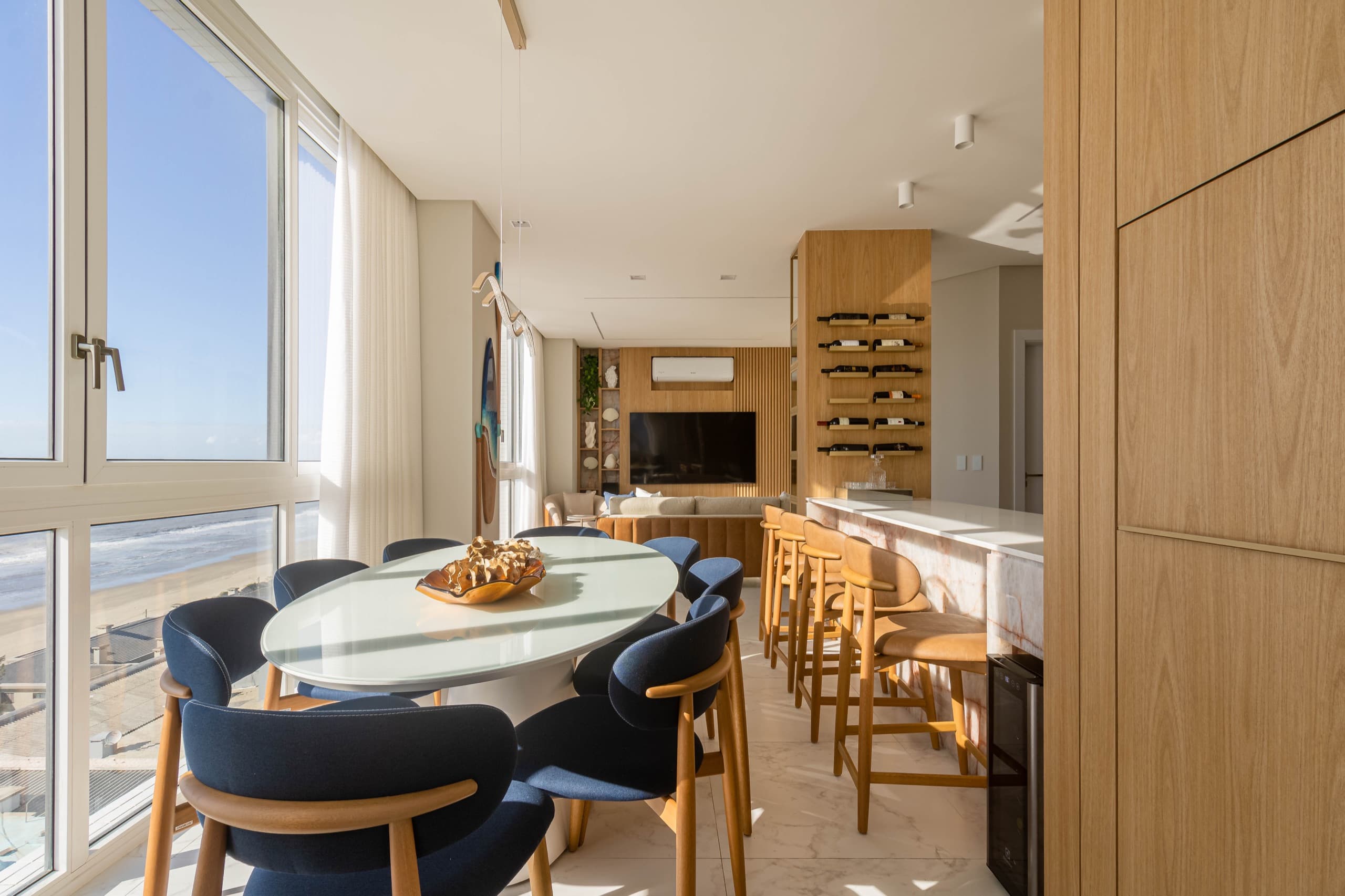 Living integrado com vista para o mar, bar em pedra e adega de vinhos em madeira sob medida