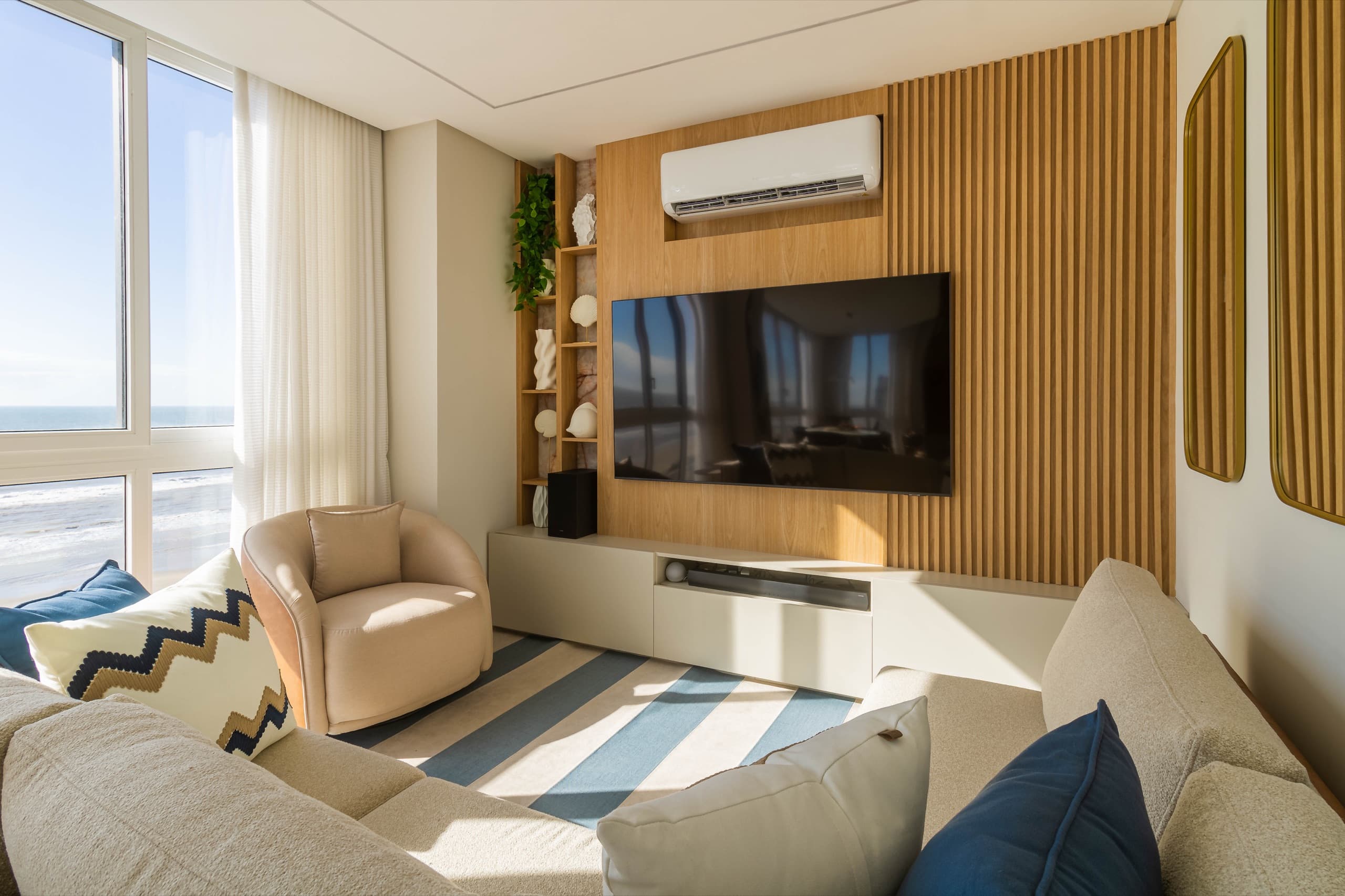 Living visto de outro ângulo, com painel de TV em madeira ripada