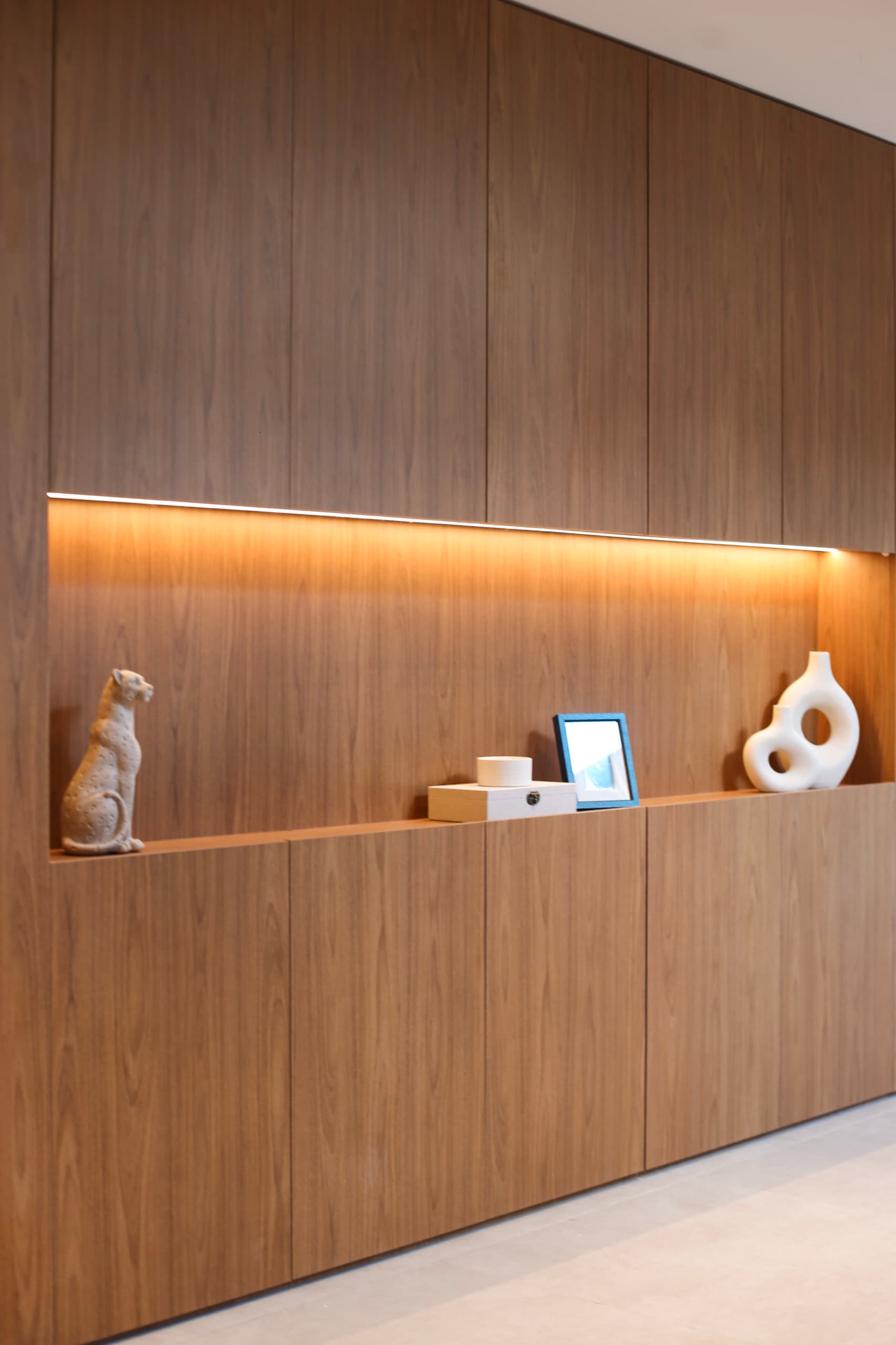 Painel em nogueira com nicho iluminado e objetos decorativos