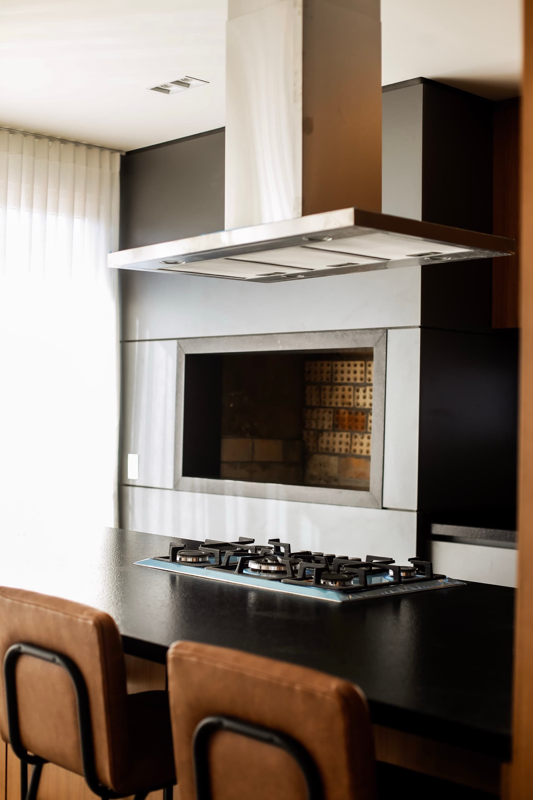 Churrasqueira e cooktop na ilha, com coifa suspensa