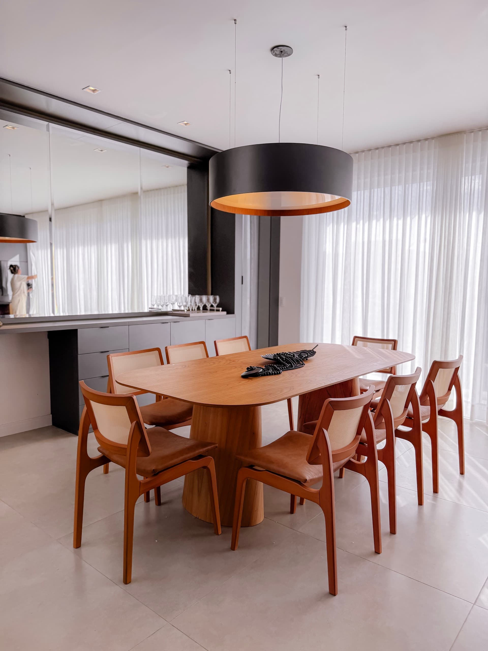 Sala de jantar com cadeiras em madeira e palhinha, buffet em grafite e cortinas ao fundo