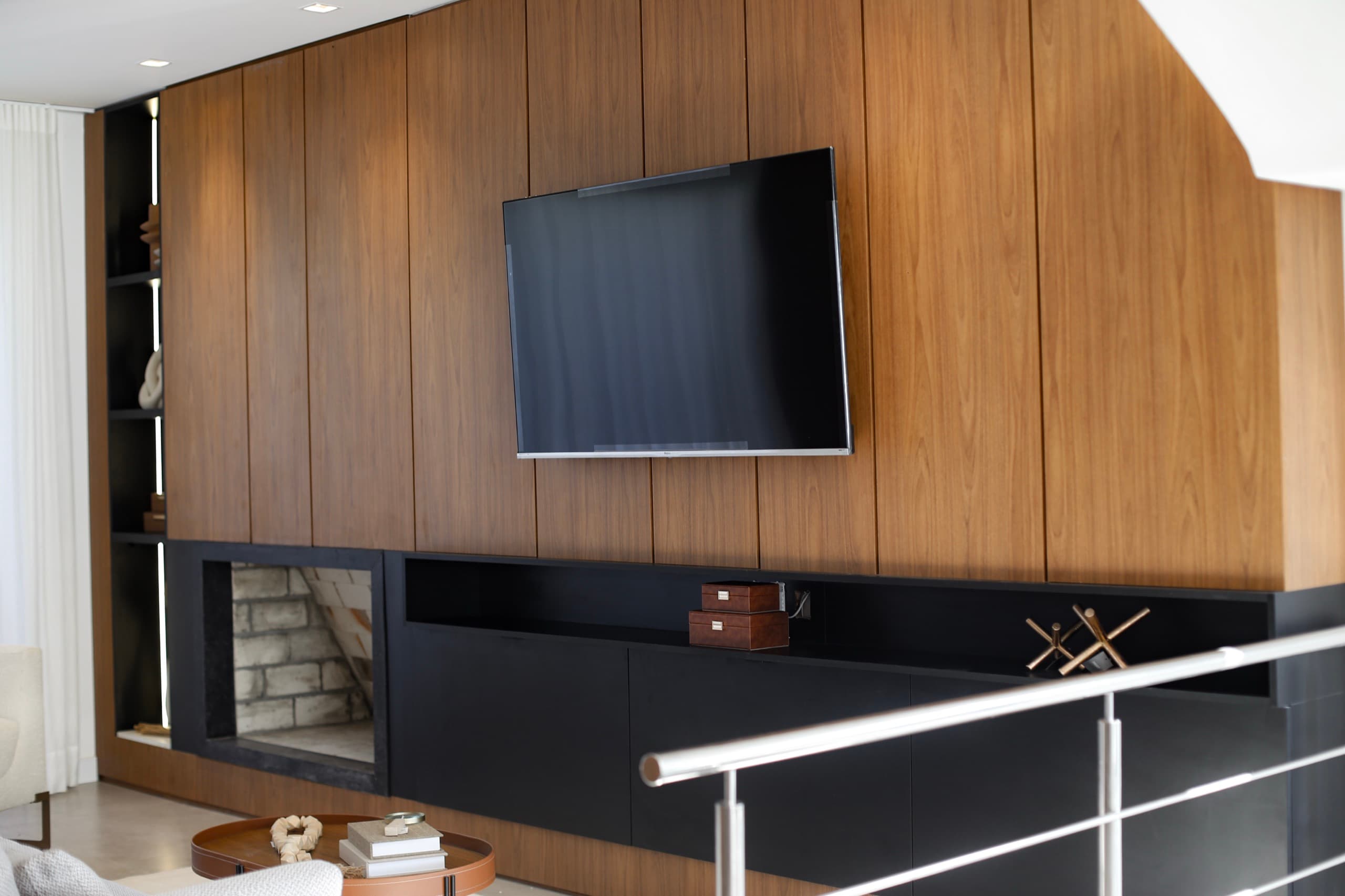 Living superior com painel em nogueira, rack preto e lareira