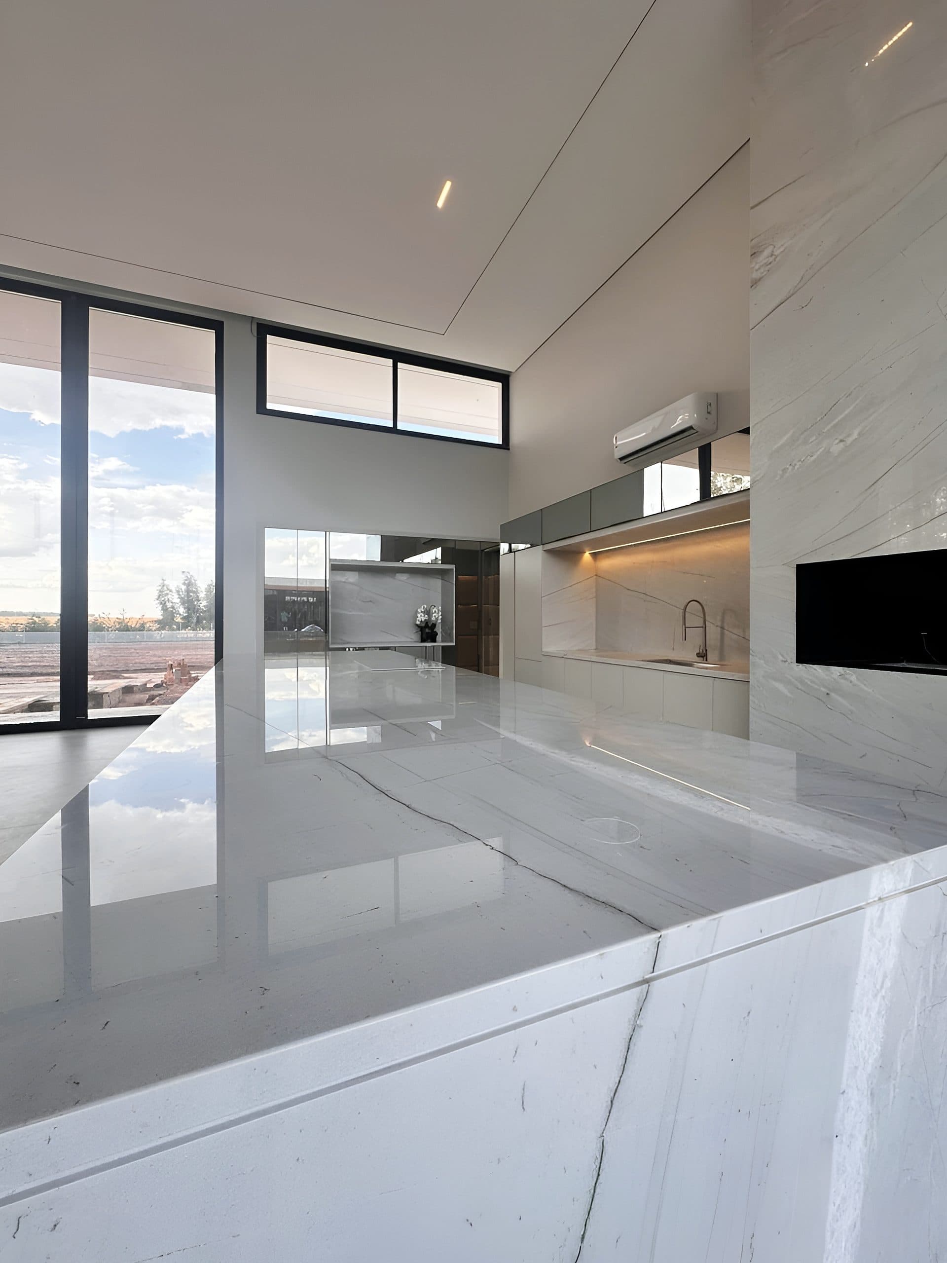 Cozinha com ilha em pedra, armários brancos e nicho iluminado — vista 4