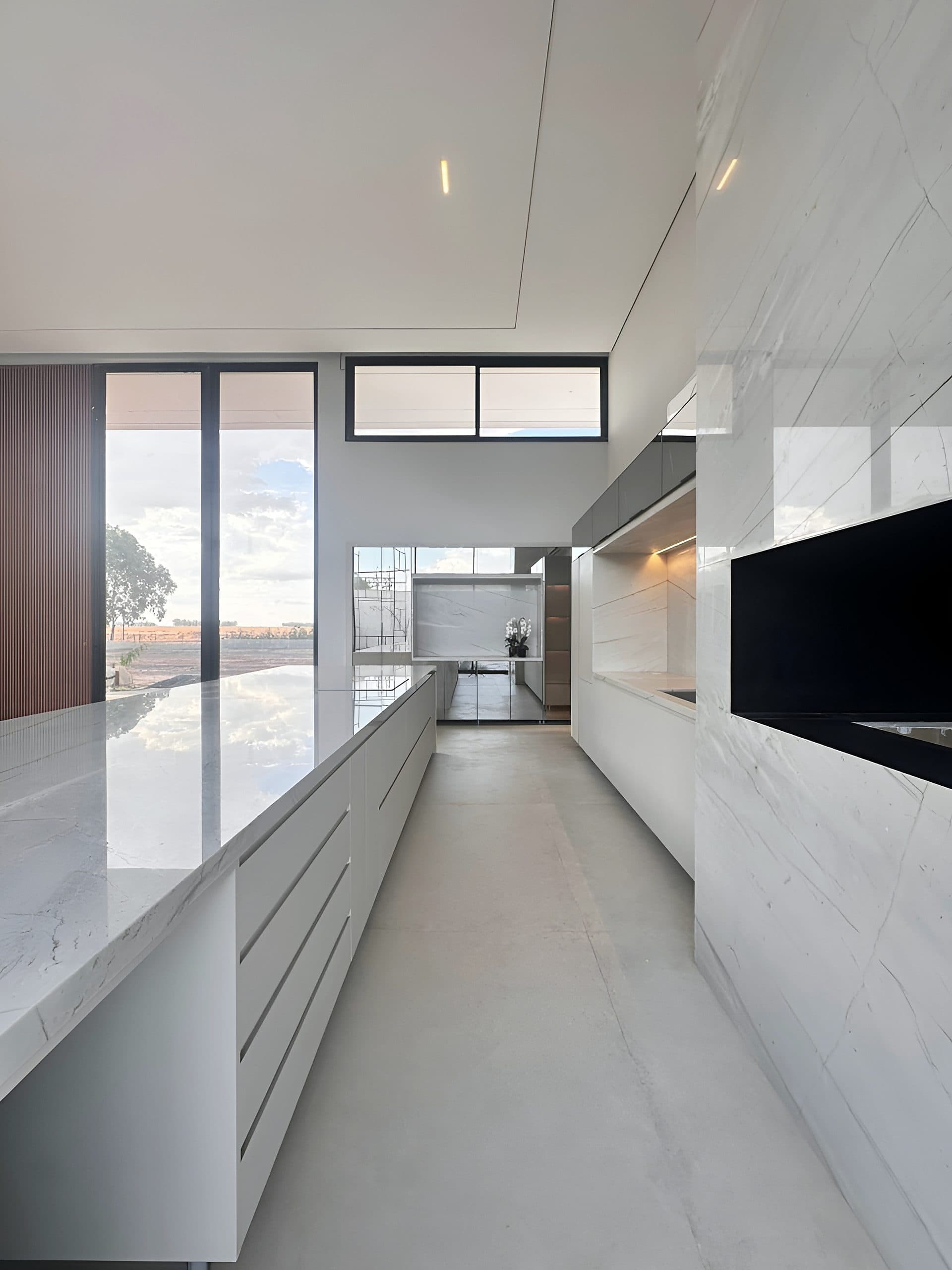 Cozinha com ilha em pedra, armários brancos e nicho iluminado — vista 6