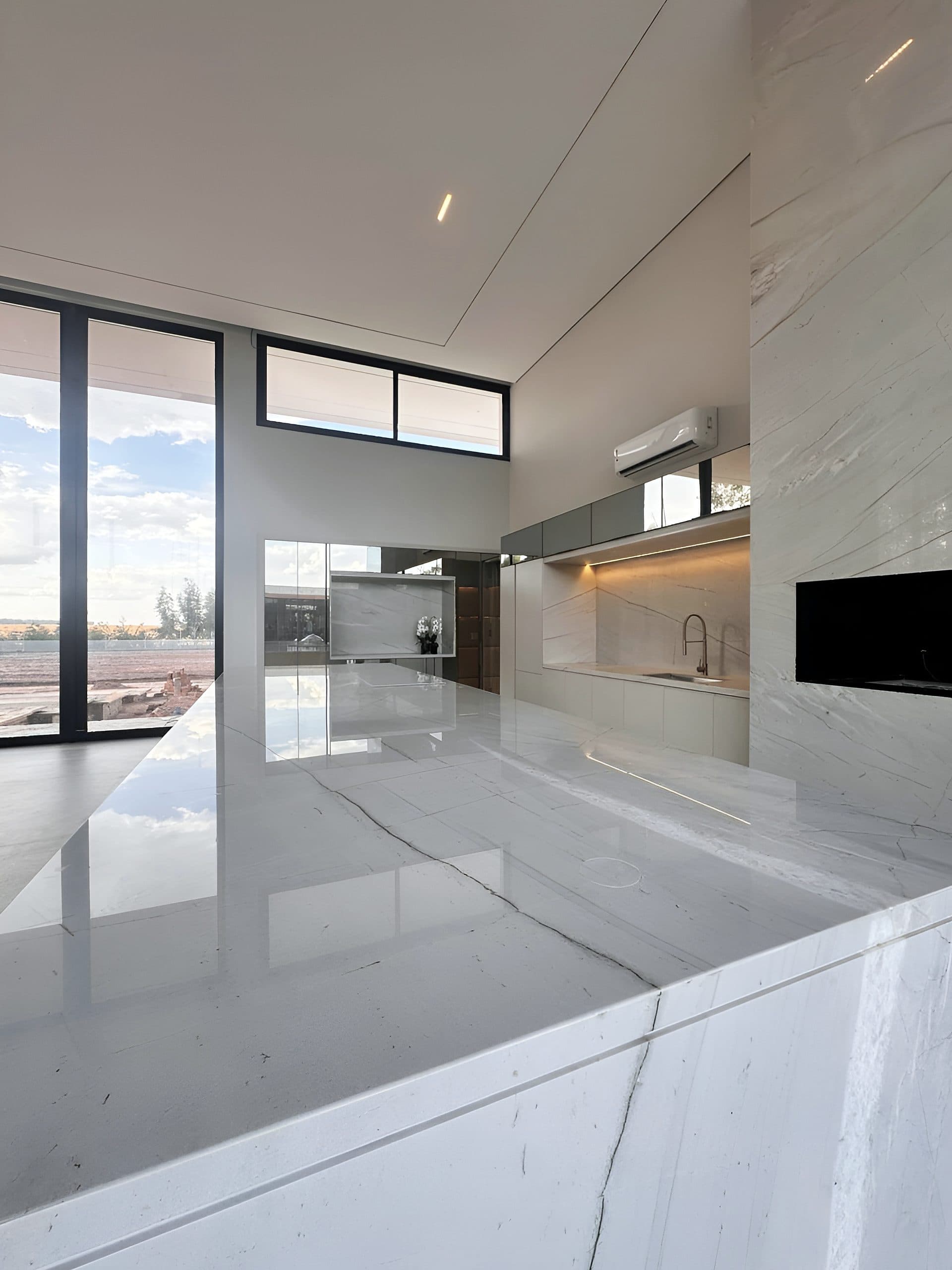 Cozinha com ilha em pedra, armários brancos e nicho iluminado — vista 7