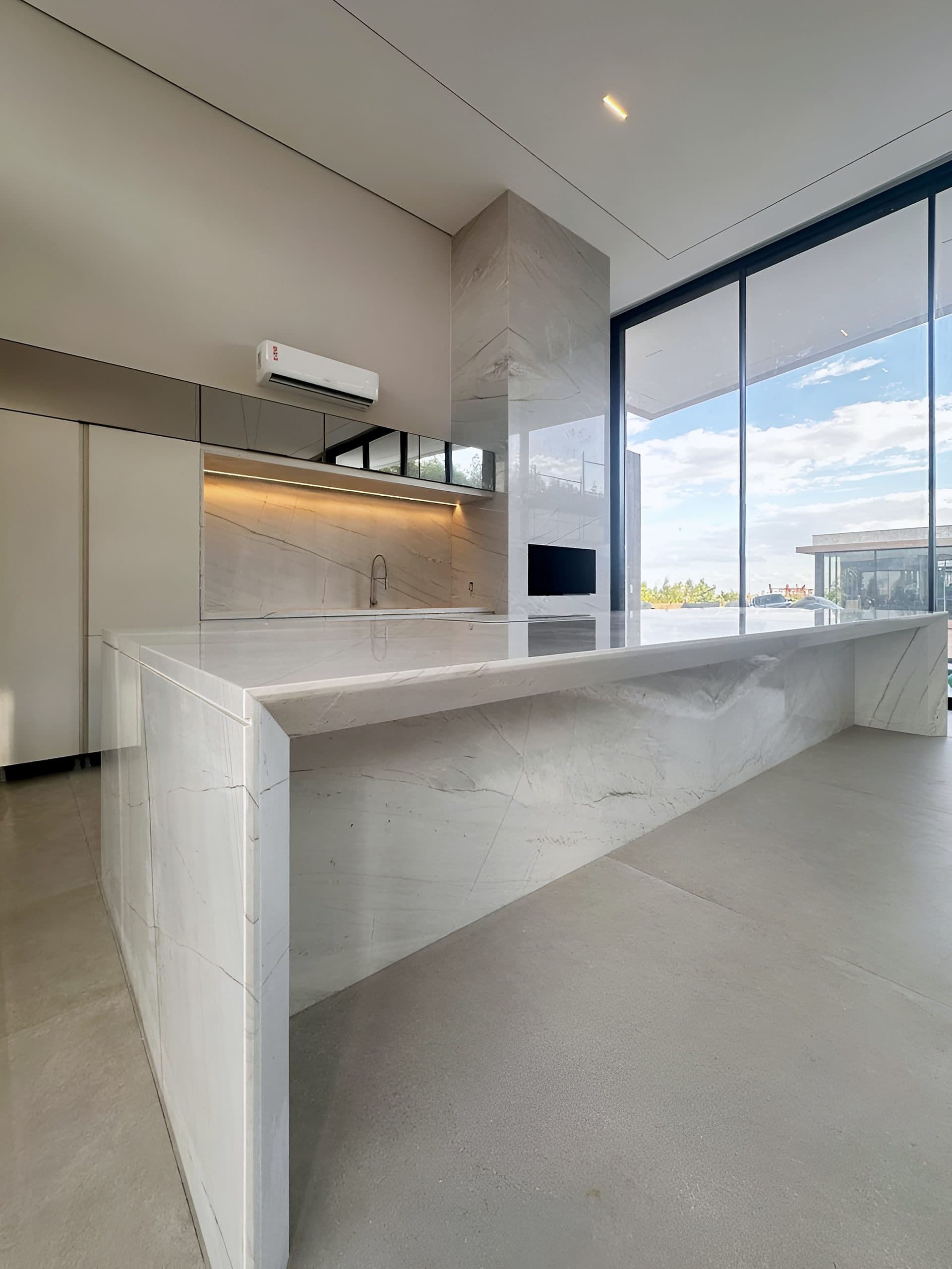 Cozinha com ilha em pedra, armários brancos e nicho iluminado — vista 8