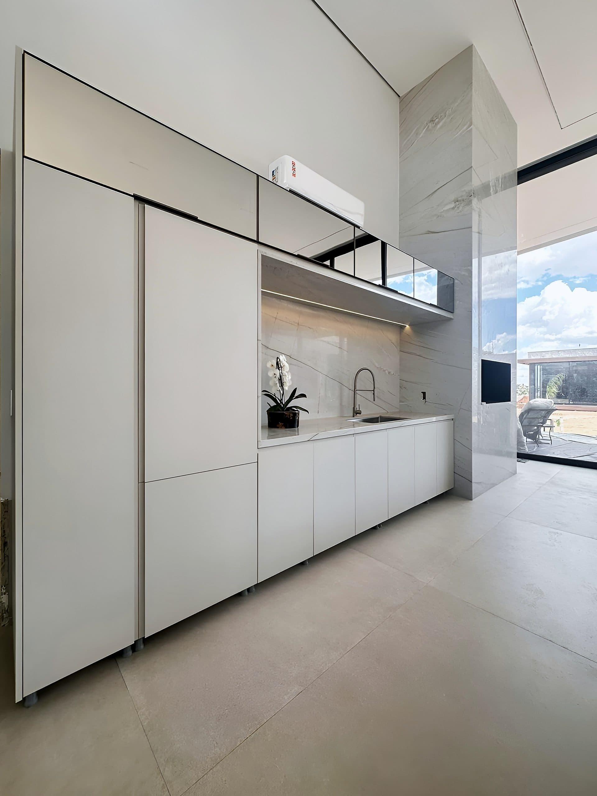 Cozinha com ilha em pedra, armários brancos e nicho iluminado — vista 12