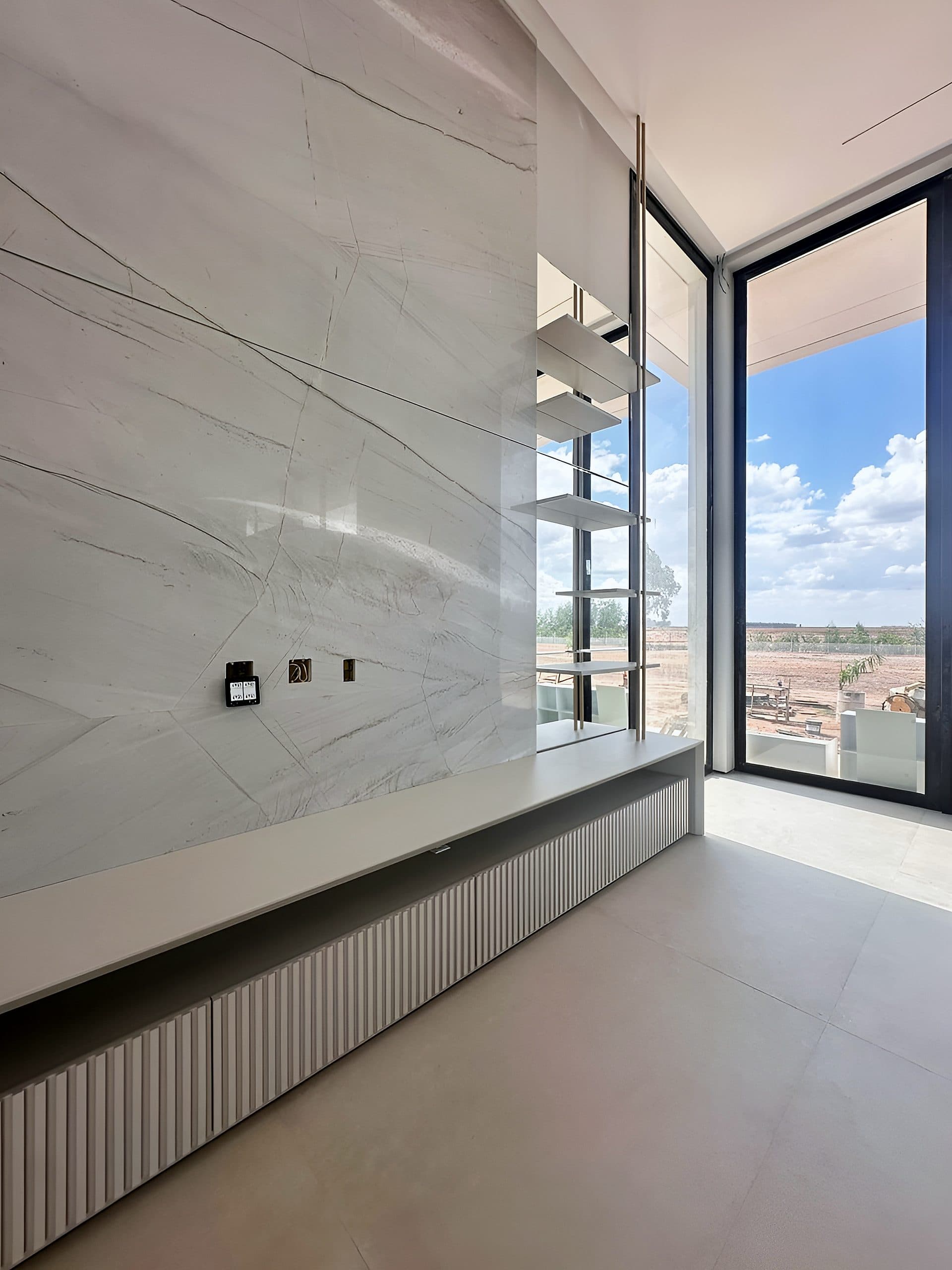 Living com painel em pedra e banco sob medida junto à janela — vista 1