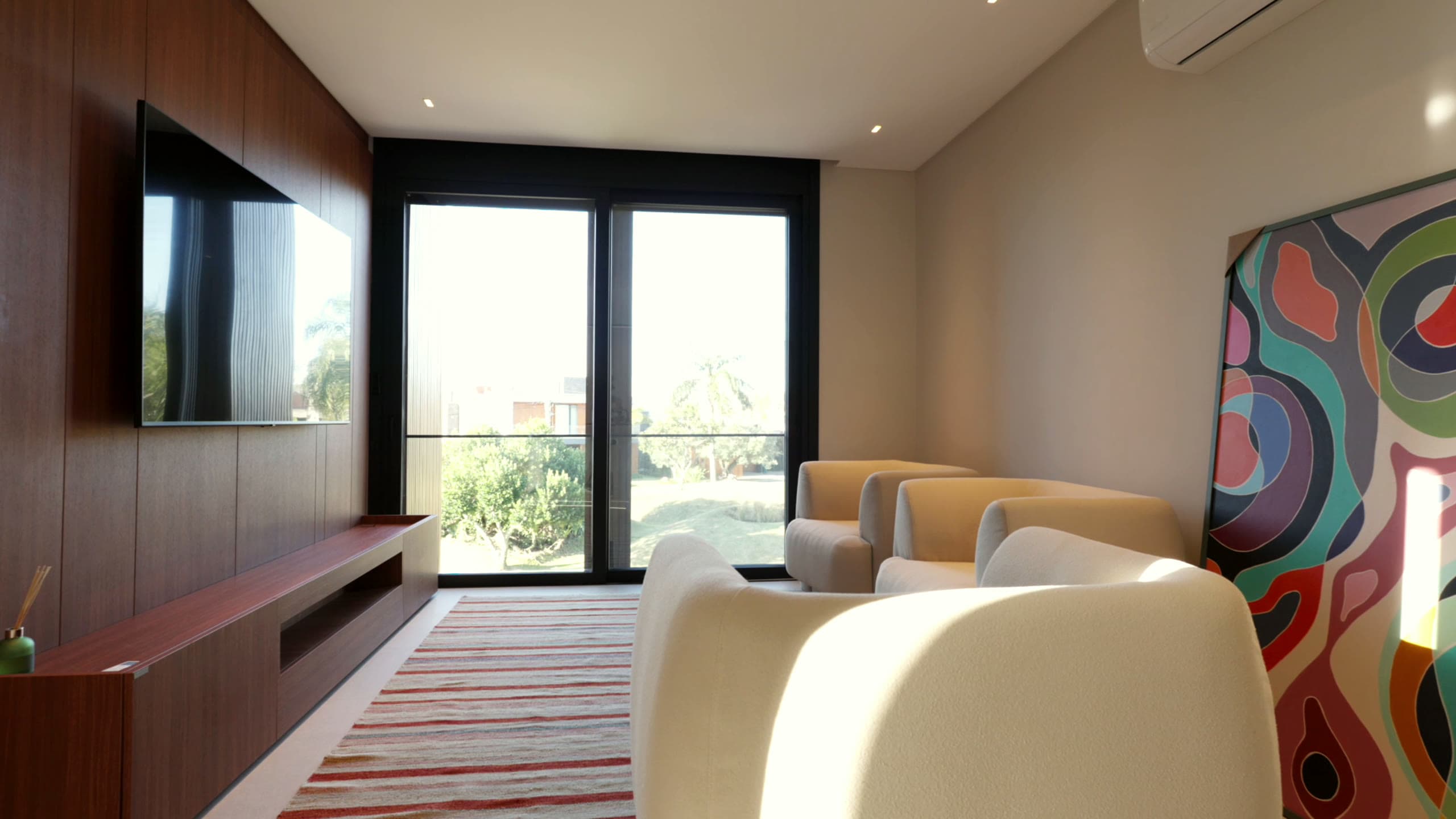 Sala de estar com painel de TV em madeira e poltronas coloridas