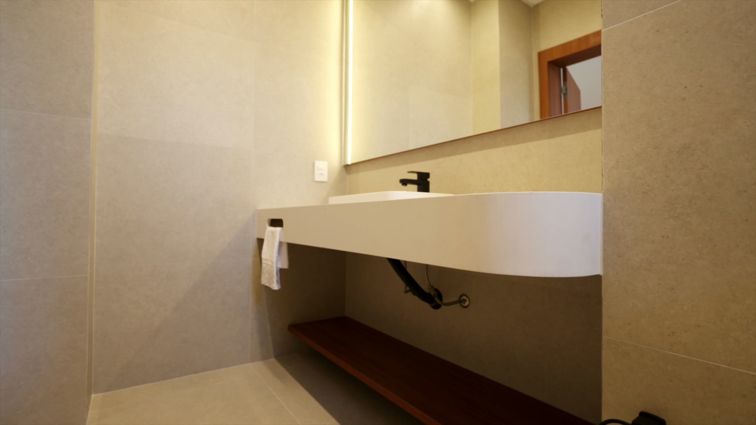 Banho com bancada suspensa em formato orgânico e espelho retroiluminado