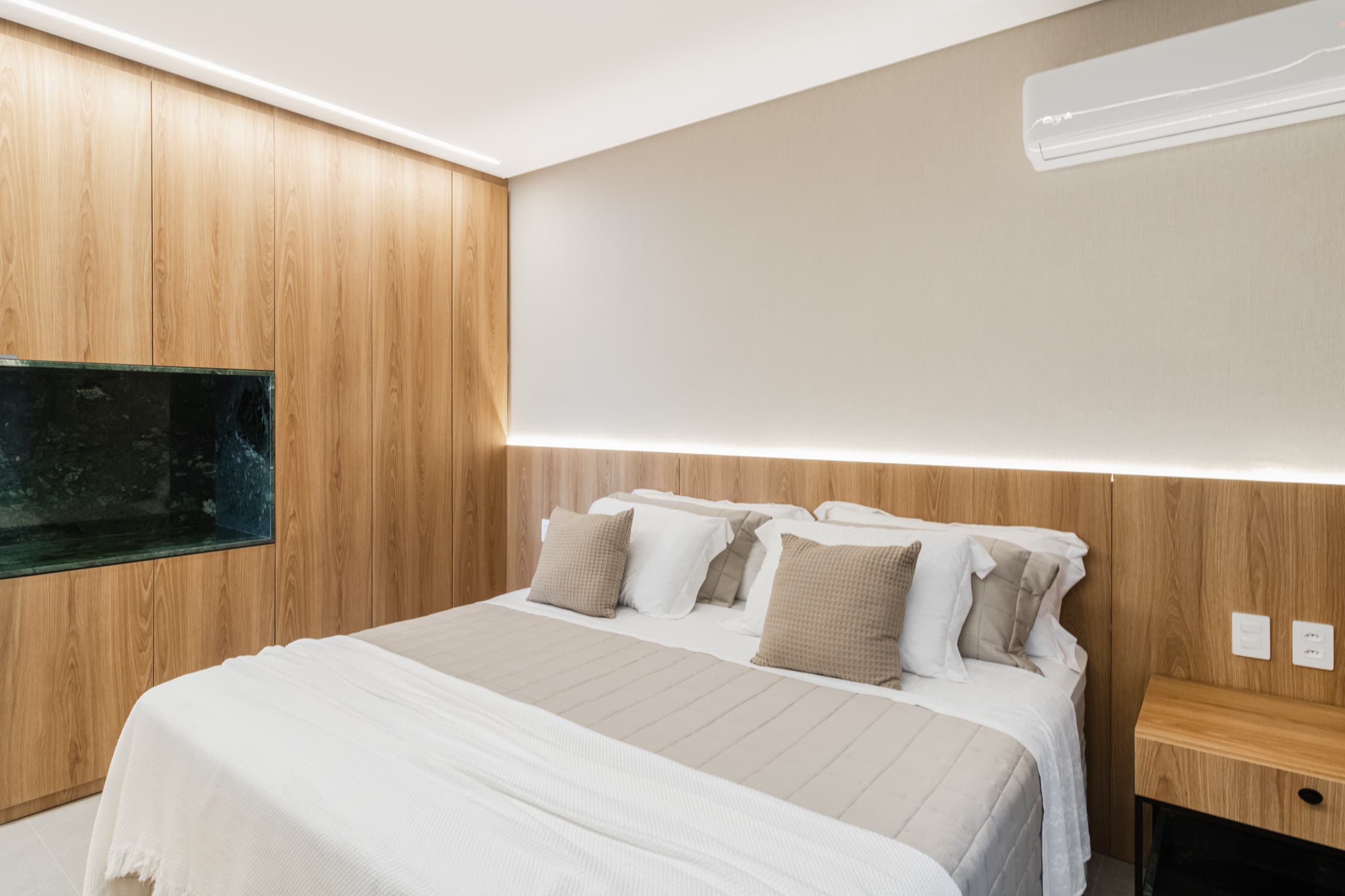 Suíte térrea com painel em madeira e iluminação embutida — vista 1