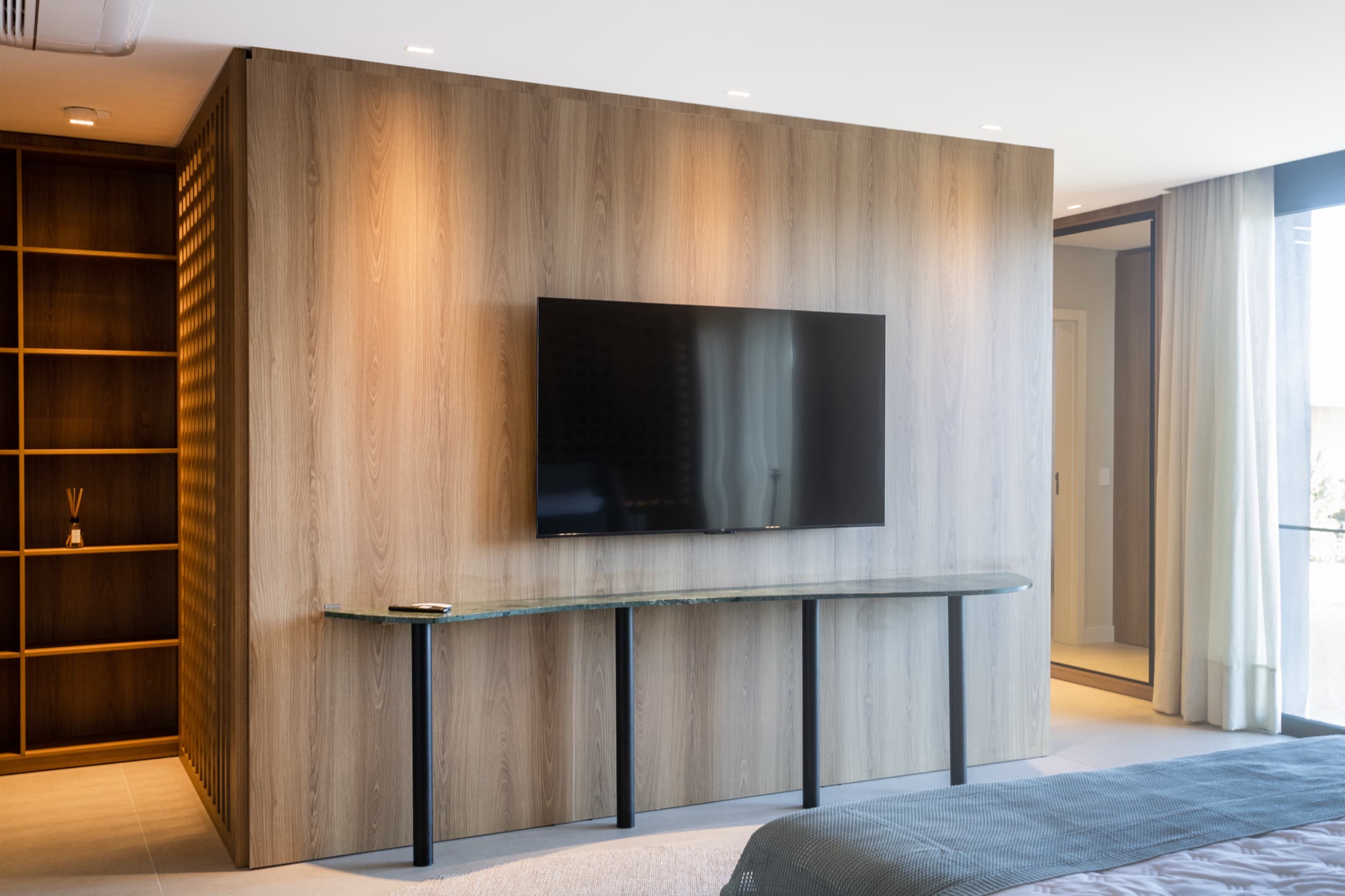 Estar da suíte master com painel de TV em madeira — vista 2