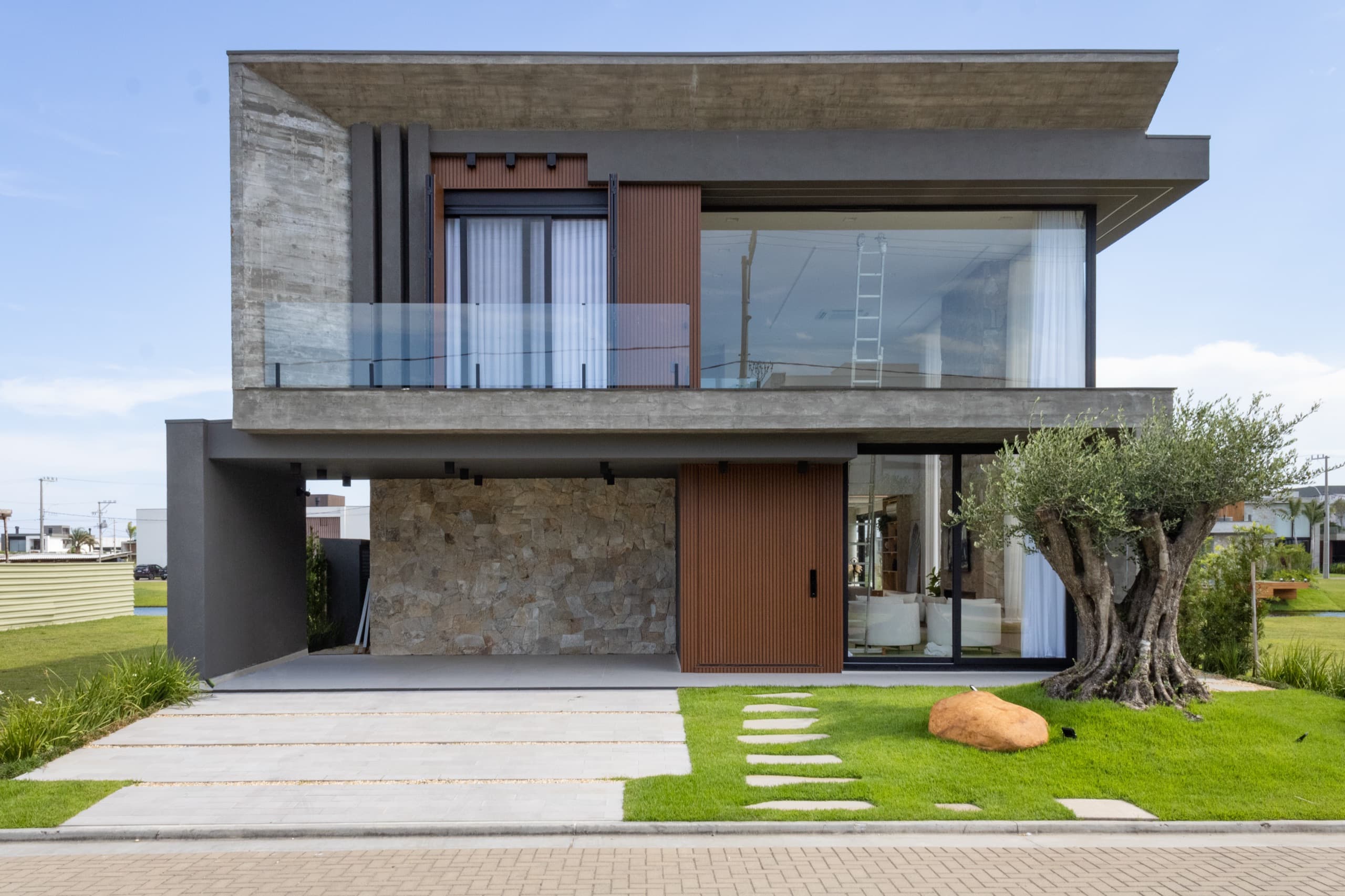 Fachada da casa com volumetria contemporânea, revestimento em pedra e iluminação noturna