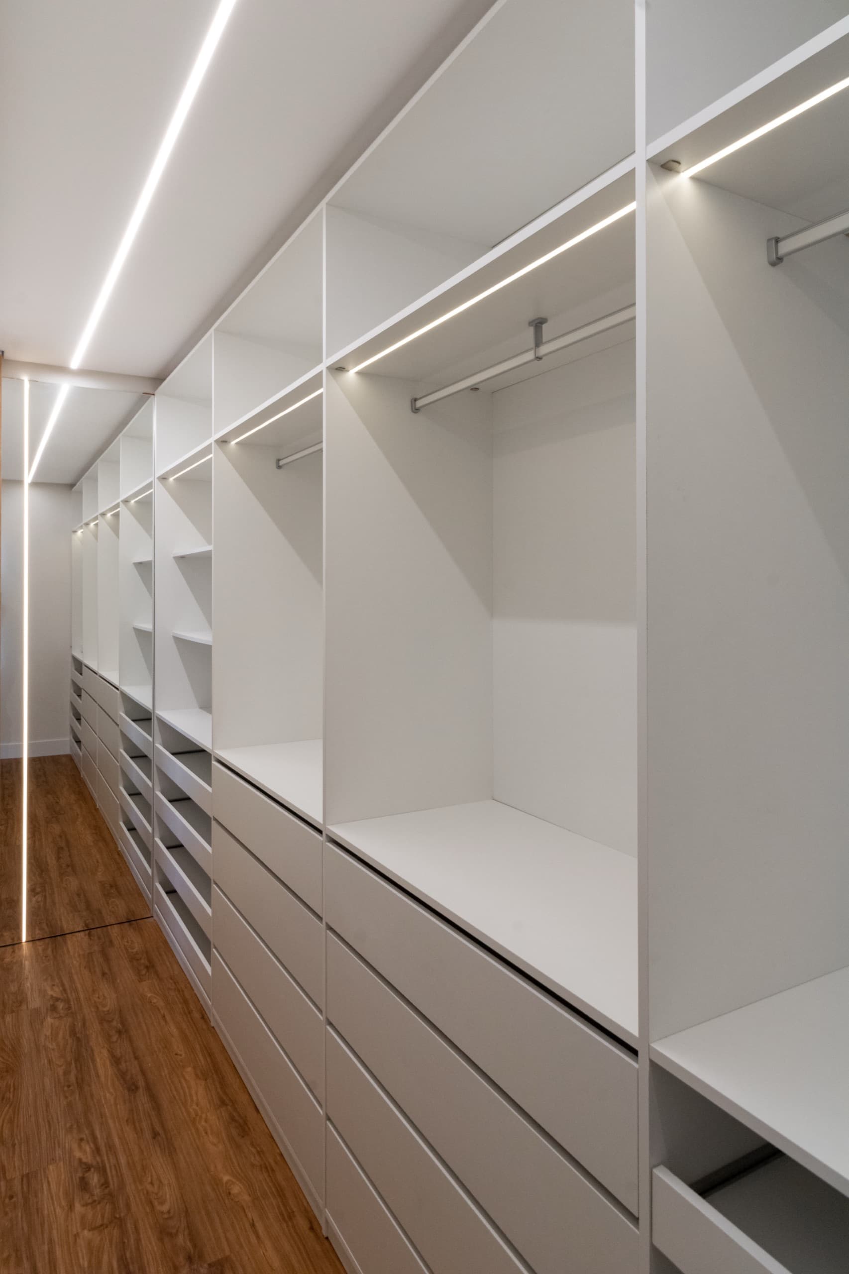 Closet da suíte de frente com armários sob medida e iluminação embutida
