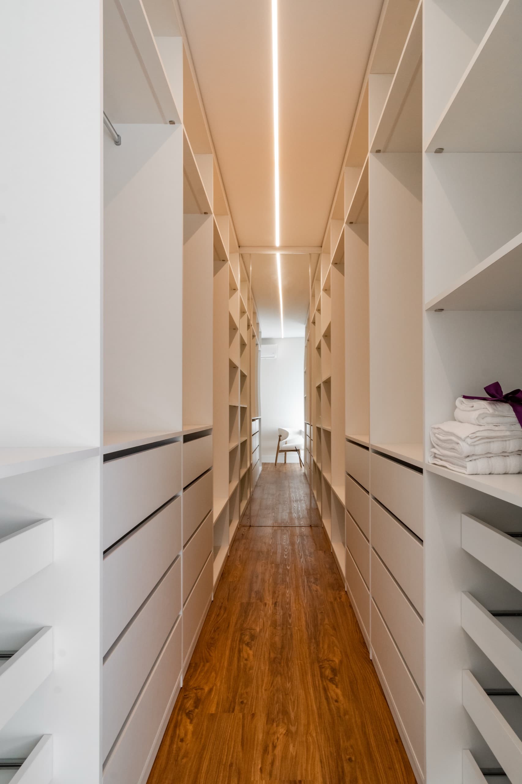 Closet da suíte master com armários sob medida e iluminação embutida