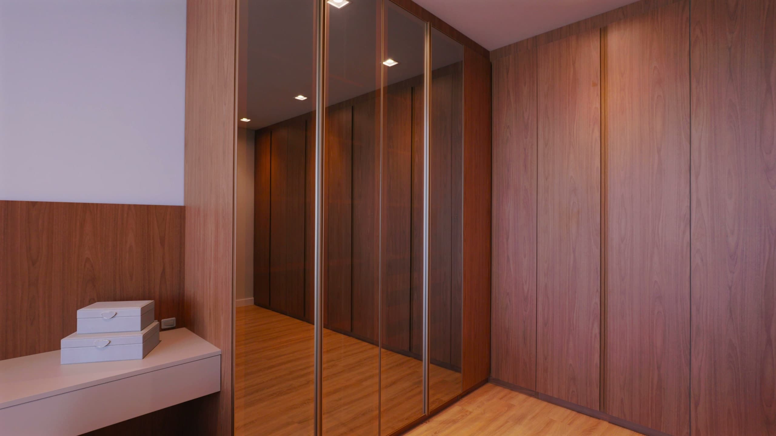 Closet em madeira com portas espelhadas de perfil dourado e bancada suspensa