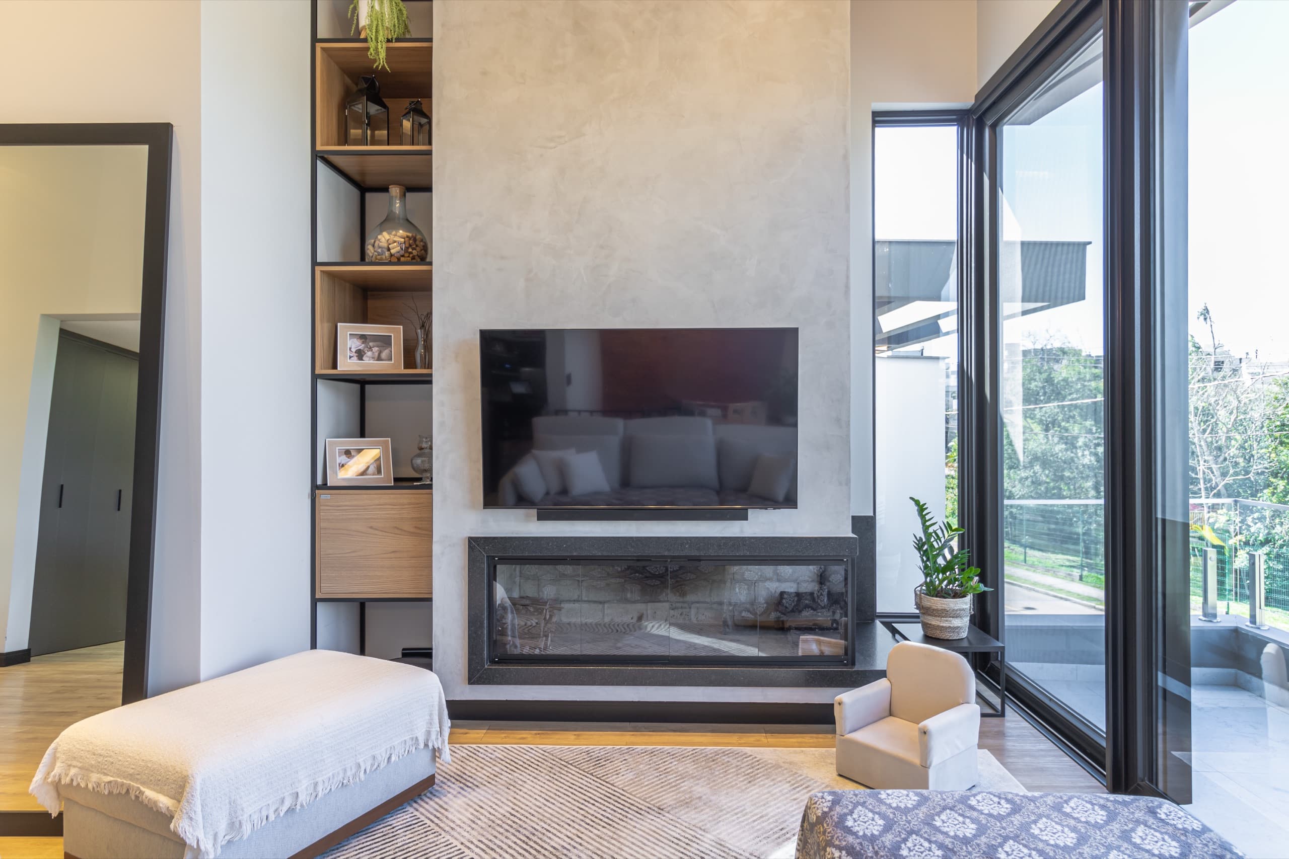 Living com lareira, painel de TV em concreto e estante sob medida com nichos